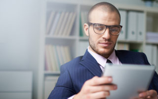 man in glasses and suit looking at a tablet