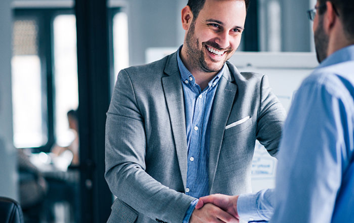 2 men smiling and shaking hands