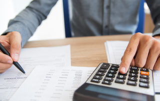 hands on calculator and writing on piece of paper